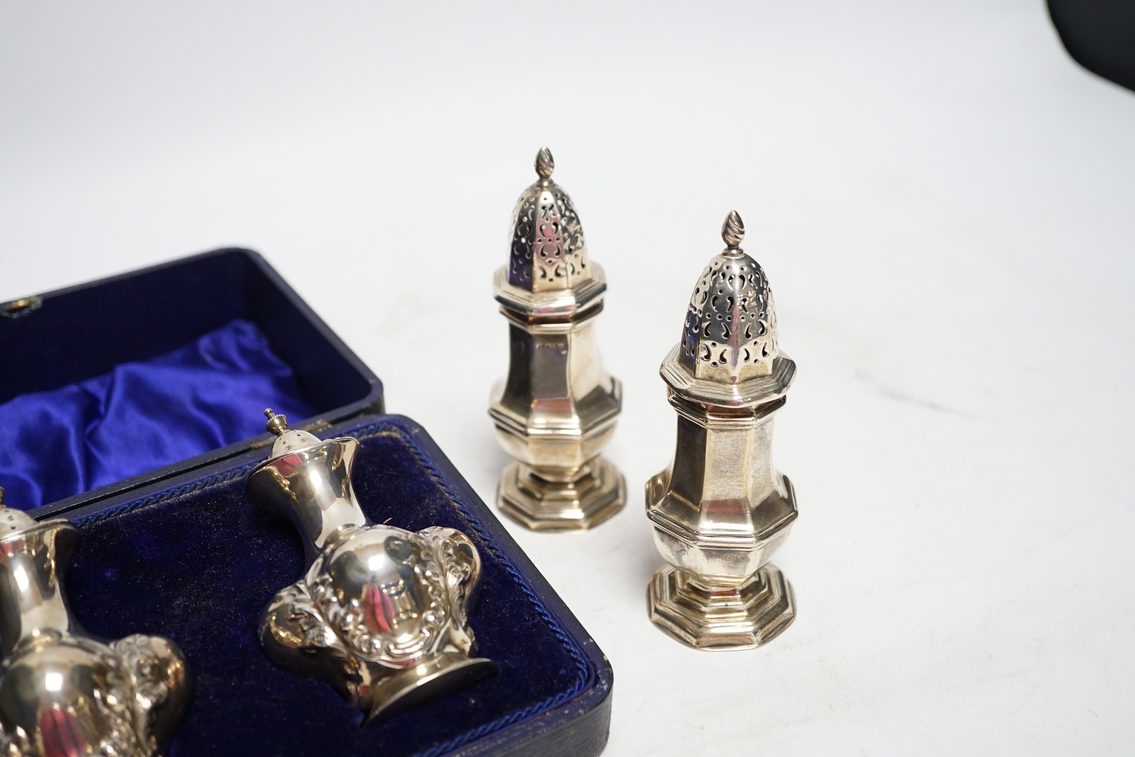 A cased pair of George V silver pepperettes, by Joseph Gloster Ltd, Birmingham, 1912, 98mm and a pair of Edwardian silver octagonal pepperettes, 6.3oz. Fair condition.